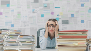 Overwhelmed woman between stacks of paper