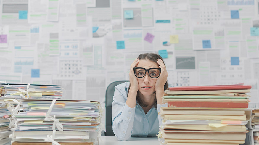 Overwhelmed woman between stacks of paper